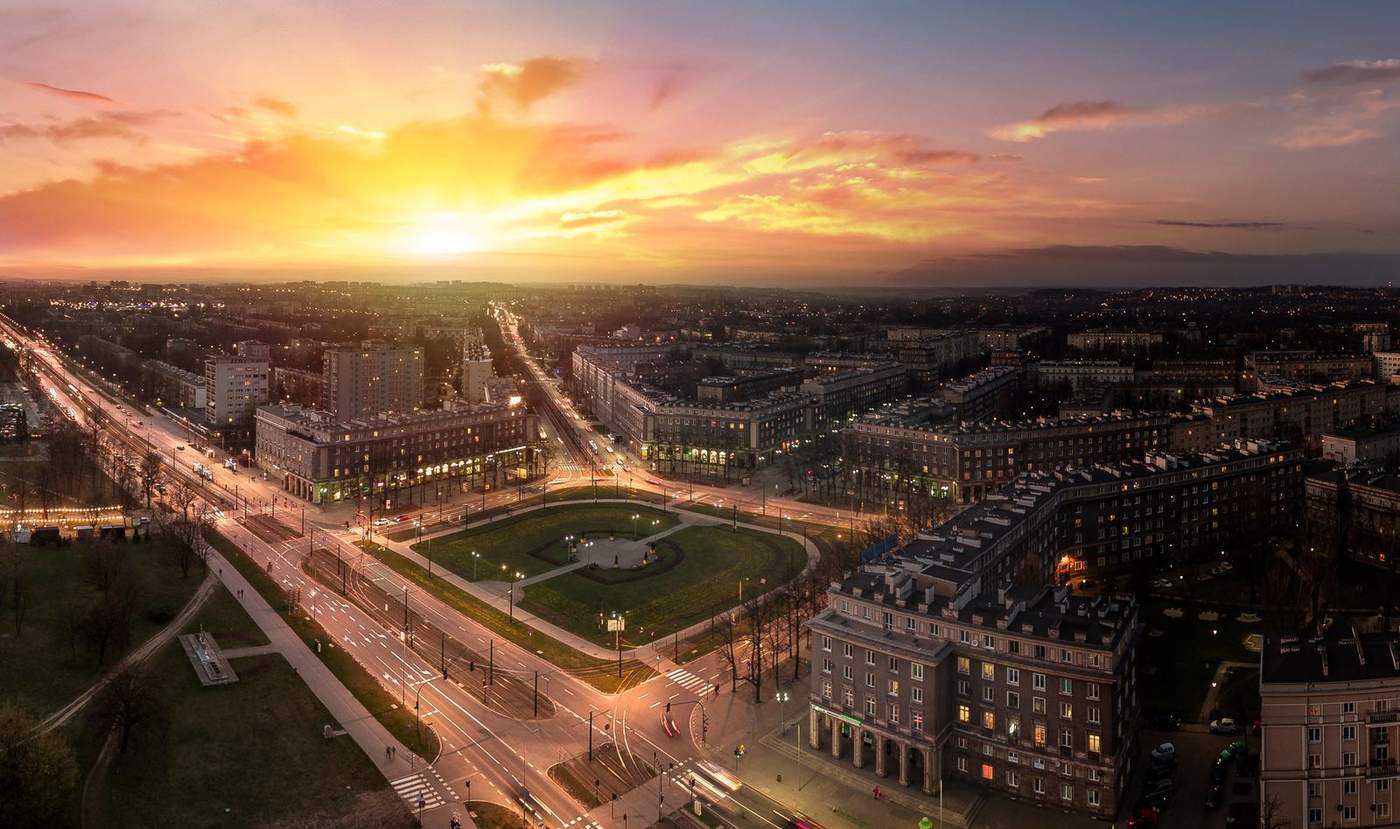 Plac Centralny w Nowej Hucie o zachodzie słońca — panorama socrealistycznej zabudowy i alei